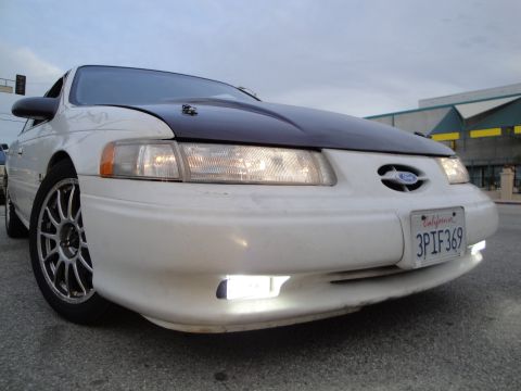 1993 Ford Taurus - A white Ford Taurus with a dark hood is shown from the front, displaying its license plate.