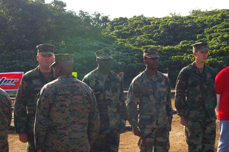 Service members in camouflage uniforms standing in formation on a dirt lot