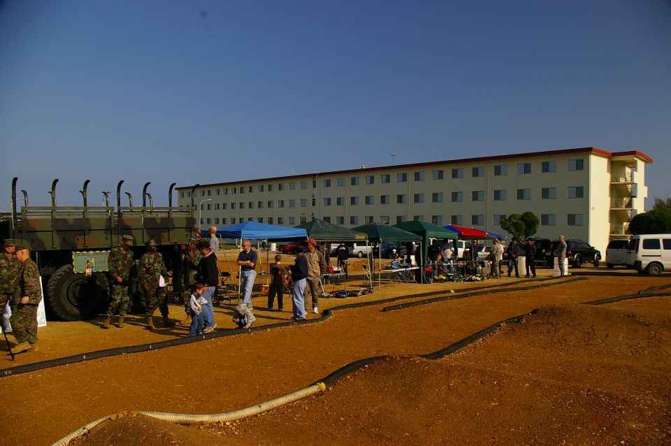 Military truck and people gathered near tents and buildings