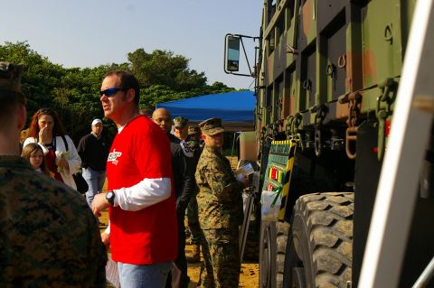 1986 Ford Bronco - A military truck is displayed outdoors with several people, some in uniform, observing it.
