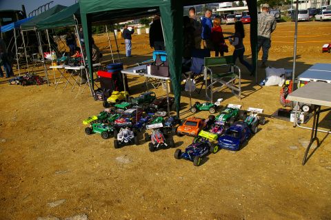 1986 Ford Bronco - Various remote control cars are laid out on the ground for display or sale at an outdoor event.