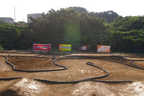 1986 Ford Bronco - A dirt track for remote-controlled cars features several sponsor banners in the background.