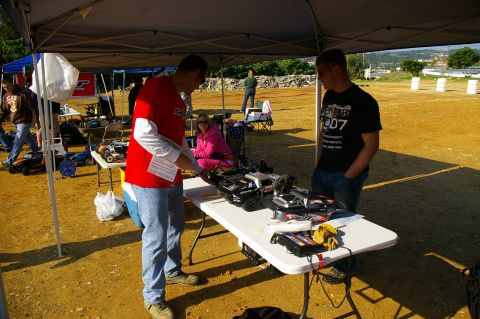 1986 Ford Bronco - People examine remote control cars at an outdoor event, with tents and barriers visible in the background.