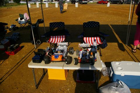 1986 Ford Bronco - Two remote control cars are set up on a table, ready for a race day event.