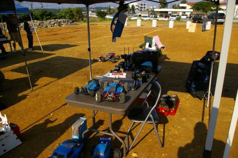 1986 Ford Bronco - Remote control cars and gear are laid out on a table at an outdoor event.