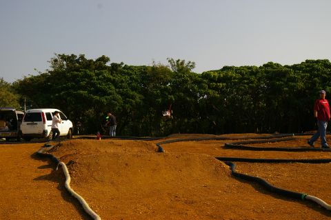 1986 Ford Bronco - People and vehicles are gathered at a remote control car track on a clear day.