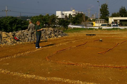 1986 Ford Bronco - A dirt track with orange hose borders is set up for remote control cars, with two people observing.