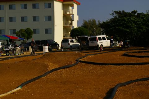 1986 Ford Bronco - RC car track setup with multiple vehicles and spectators in the background.