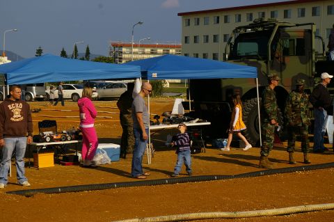 1986 Ford Bronco - An outdoor event features remote control cars and a large military vehicle, with spectators observing.