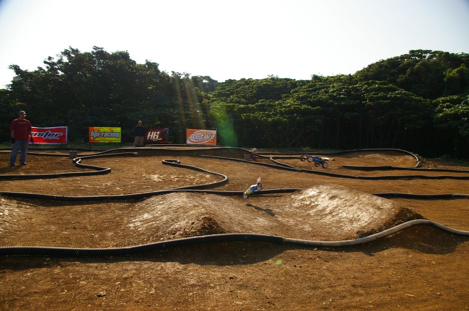 Remote control cars racing on a dirt track with trees in the background
