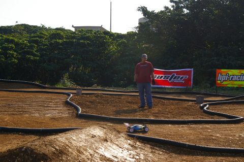 1986 Ford Bronco - A remote control car navigates a dirt track, with a person observing and banners in the background.