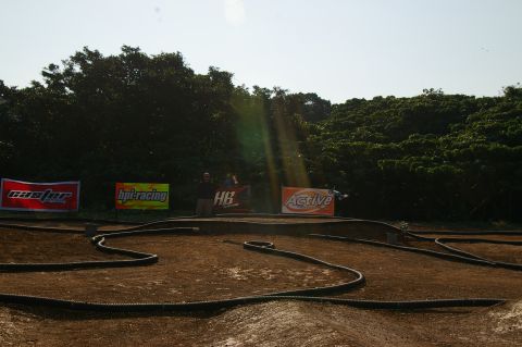 1986 Ford Bronco - An outdoor remote-controlled car track is set up with various sponsor banners in the background.
