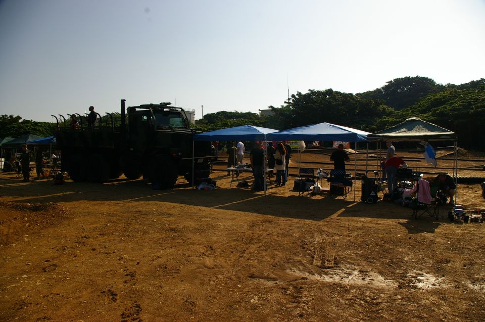 Military truck parked at an outdoor event with tents and people