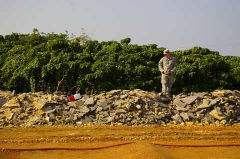 1986 Ford Bronco - A soldier surveys a debris-filled landscape under a clear sky.