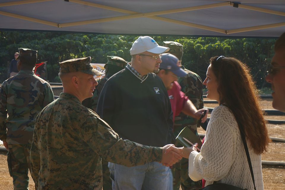 People in military uniforms and civilian clothes interacting under a tent