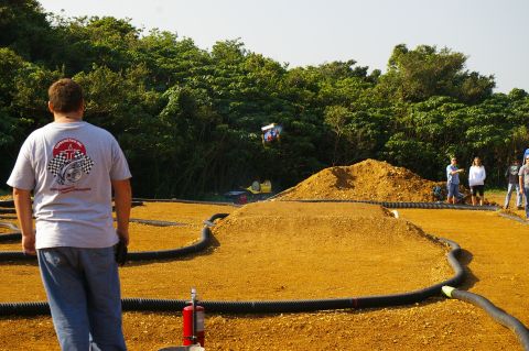 1986 Ford Bronco - A remote control car is captured mid-air during a race on a dirt track.