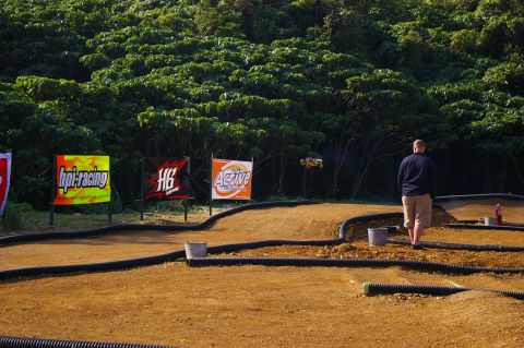 1986 Ford Bronco - RC car jumps over dirt track, with sponsor banners visible.