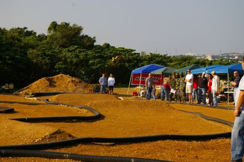 1986 Ford Bronco - Spectators and participants observe a remote control car race on a custom-built dirt track.