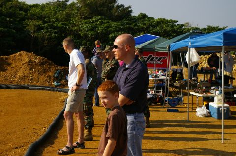 1986 Ford Bronco - Spectators gather at an outdoor event, observing remote control cars race on a dirt track.