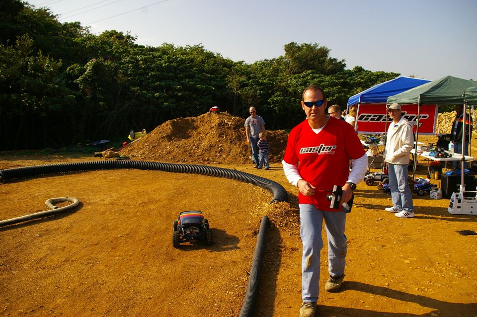 RC car on dirt track with people and tents in background