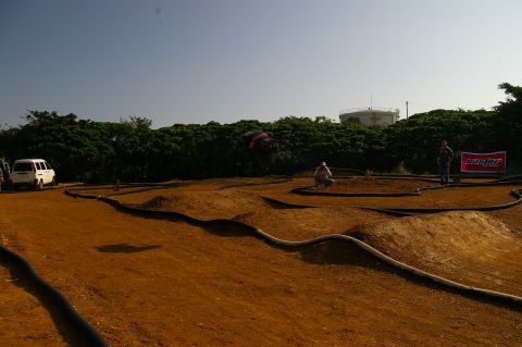 1986 Ford Bronco - A remote control car track with a white van parked nearby and two spectators observing the course.