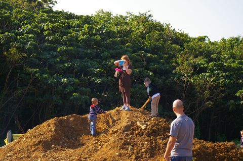1986 Ford Bronco - Children explore a large dirt pile in front of a lush green forest on a sunny day.