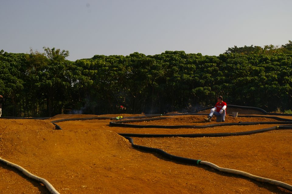 guy sitting by an RC car track with trees in the background