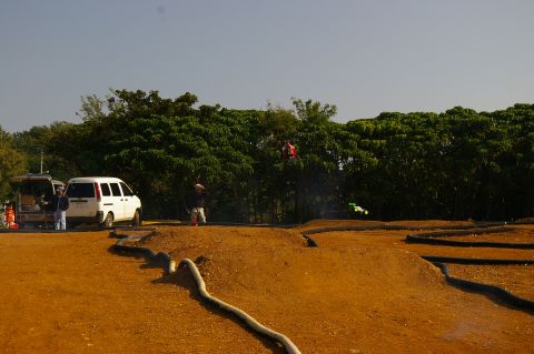 1986 Ford Bronco - A scene at a remote control car race track, with two vans parked nearby and several cars in action.