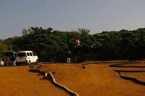 1986 Ford Bronco - Two vans are parked near a dirt track with trees in the background.