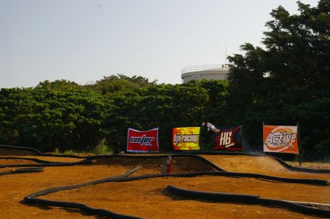 1986 Ford Bronco - Remote control car airborne over a dirt track, with sponsor banners in the background.