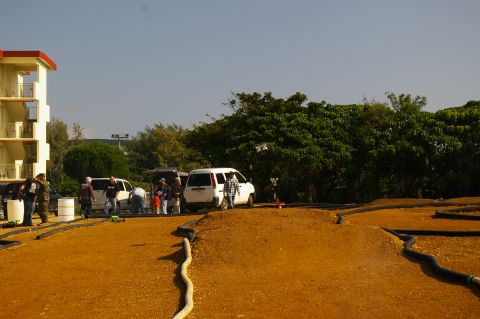 1986 Ford Bronco - A group of people and several vans are gathered near a dirt track, possibly for a remote control car event.