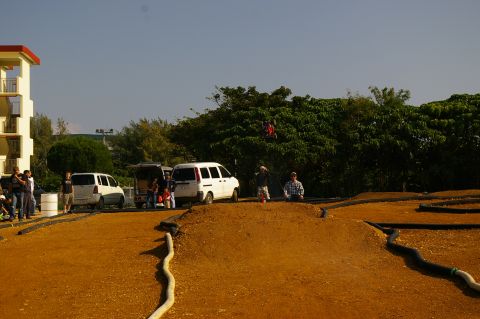 1986 Ford Bronco - A dirt track for remote control cars is visible with several vans and people gathered around.