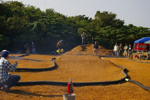 1986 Ford Bronco - RC car racing event with spectators gathered around the dirt track.