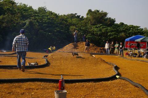 1986 Ford Bronco - Spectators gather to observe a remote control car race on a custom dirt track.