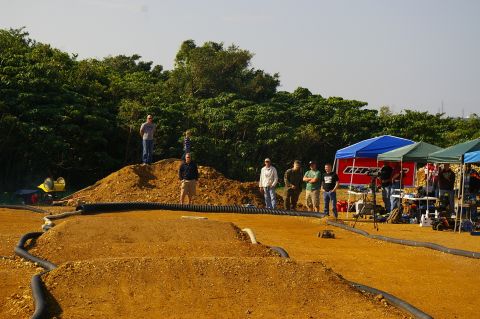 1986 Ford Bronco - Spectators gather to watch a remote control car race event on a custom dirt track.