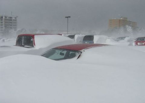 1991 Ford Crown Victoria - A blizzard has completely covered parked vehicles, leaving only their tops peeking out from the snow.
