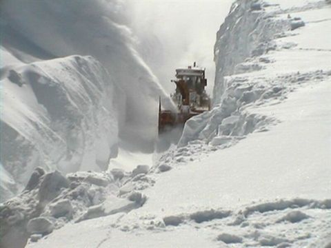 1991 Ford Crown Victoria - A snow blower operates in a snowy environment, clearing a path through deep snowdrifts.