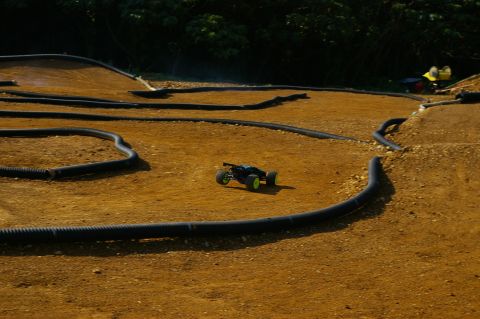 1986 Ford Bronco - A remote control buggy navigates a dirt track marked with black tubing.