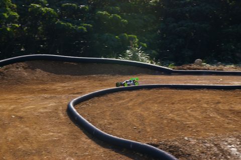1986 Ford Bronco - A remote control buggy races on a dirt track with black tubing borders.