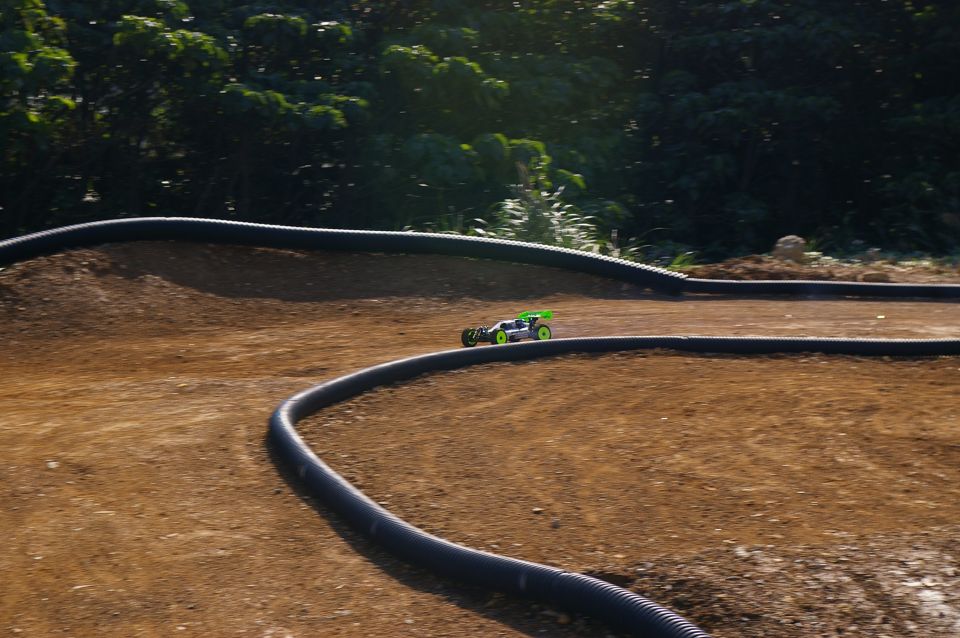 Remote control buggy with green spoiler on dirt track