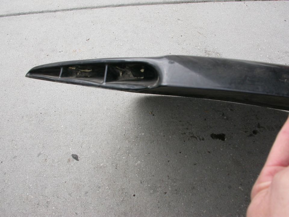 Black car part with internal divisions, angled view on concrete