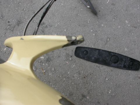 1968 Mercury Cougar - A fragment of a beige car fender lies on concrete next to a detached black trim piece.