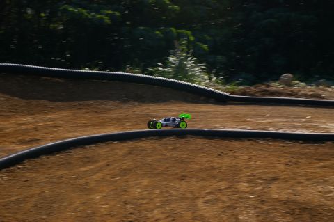 1986 Ford Bronco - A remote control buggy races along a dirt track with black curbing.