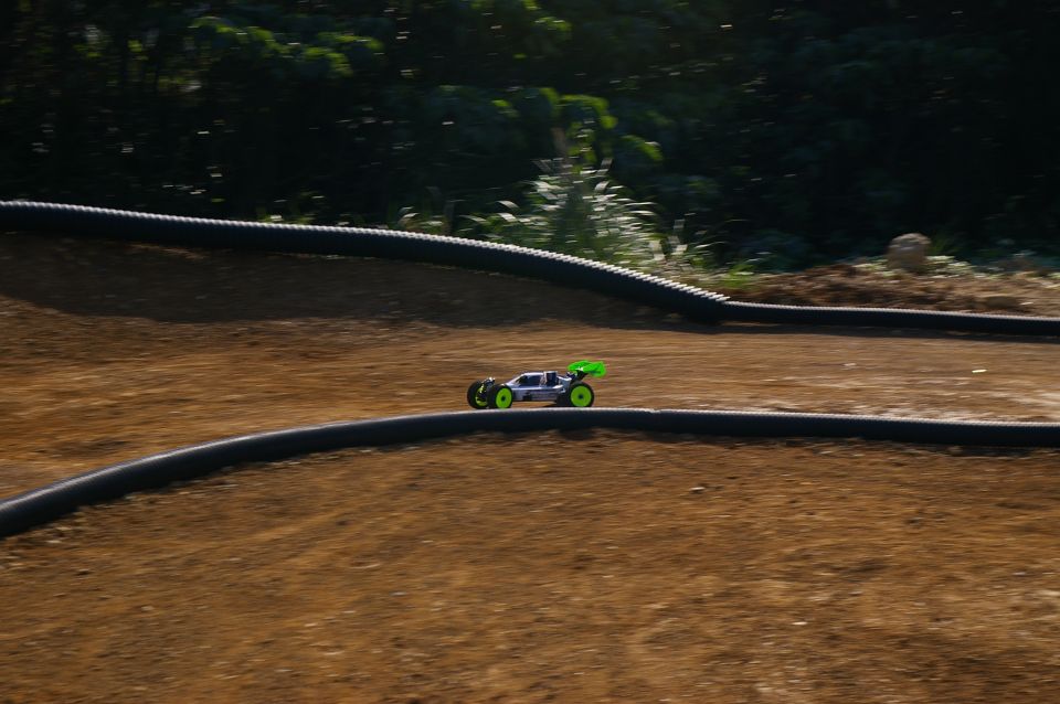 Silver remote control buggy with green spoiler on dirt track