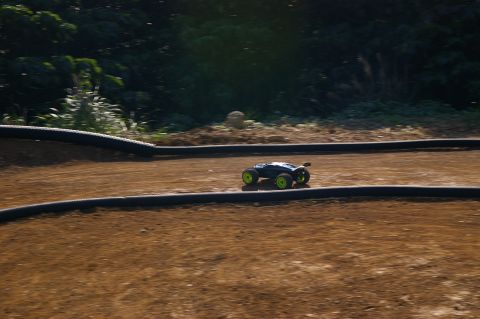 1986 Ford Bronco - RC buggy races on a dirt track with black tire barriers.