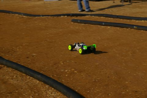 1986 Ford Bronco - A remote control buggy races on a dirt track with black tubing defining the course.