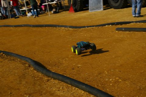 1986 Ford Bronco - A remote control monster truck races on a dirt track with black tubing lining the course.