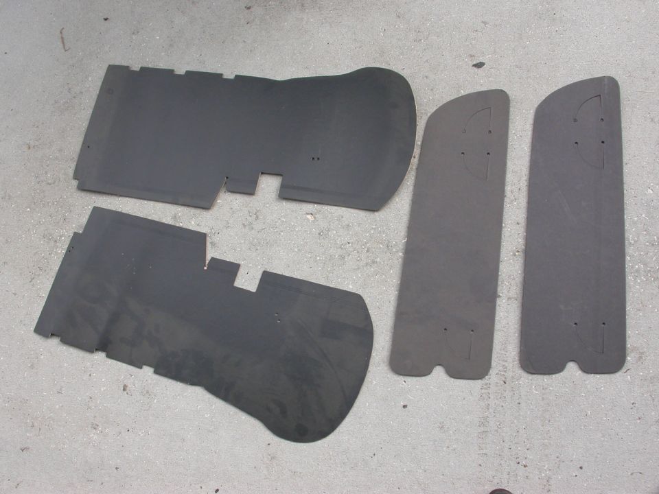 Four black rubber car floor mats on a concrete surface
