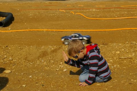 1986 Ford Bronco - A boy watches a remote control truck race on a dirt track.