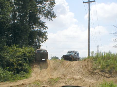1983 Ford Bronco - Two SUVs navigate a challenging off-road course on a sunny day.